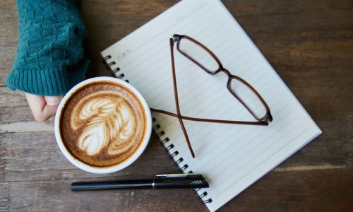 journal pen glasses coffee on table