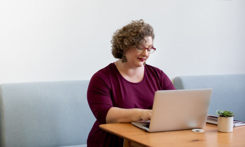 woman sitting on desk with computer