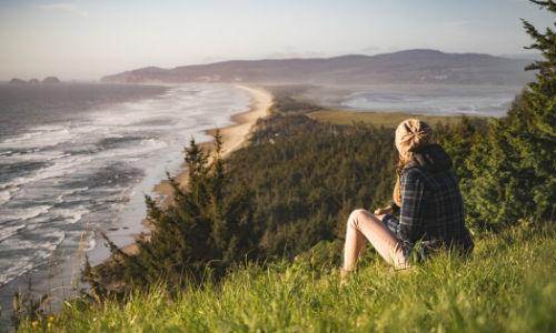 woman sitting on grass looking at the ocean