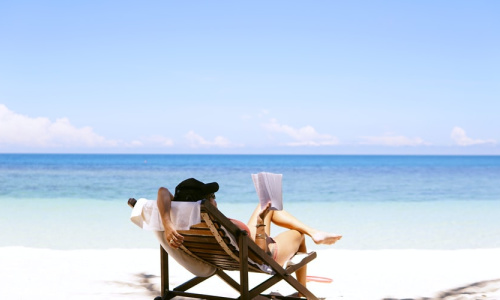woman on the beach sunbathing while readina a book