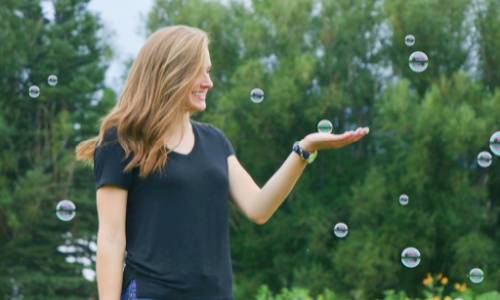 woman smiling and catching soap bubbles