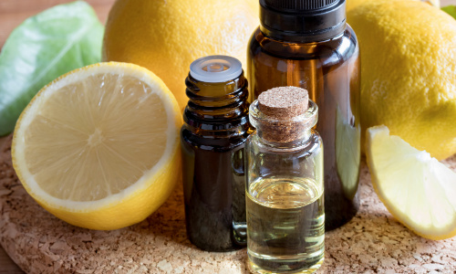 Bottles of lemon essential oil with fresh lemons