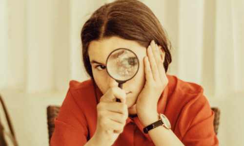 woman peering through magnifying glass