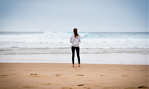 woman standing on the shoreline looking at the ocean