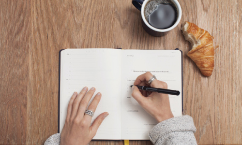 woman writing goals in journal