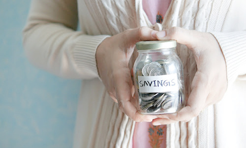 woman holding a jar with money marked savingss