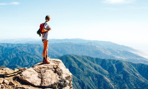 woman standing at highest point after hiking