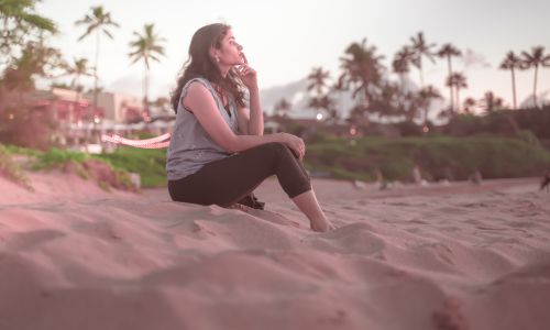 woman in deep thought sitting on the beach