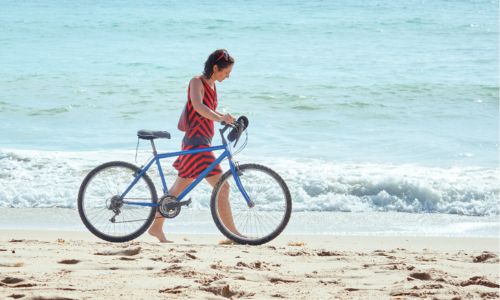 woman walking on the beach with her bike