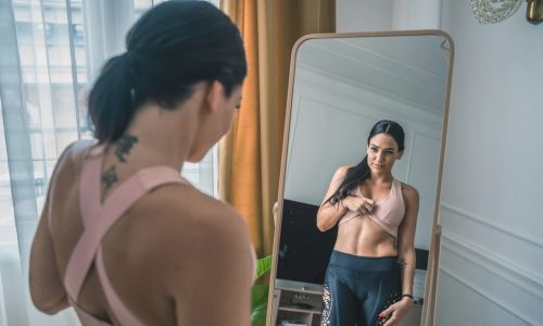 woman thoughtfully looking in mirror at herself