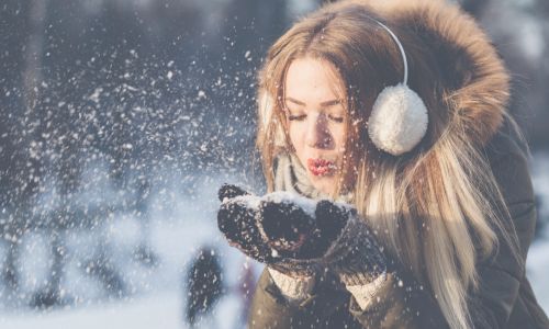 woman wearing ear muffs playing in the snow